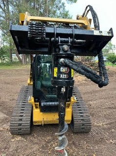 CAT skid steer with auger attachment drilling post holes — Brisbane